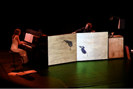 comédien sur scène, et une femme au piano