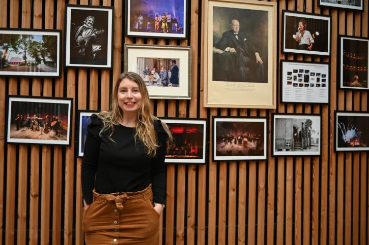 chargée de la logistique accueil artiste du spectacle vivant devant des cadres photos dans le théâtre